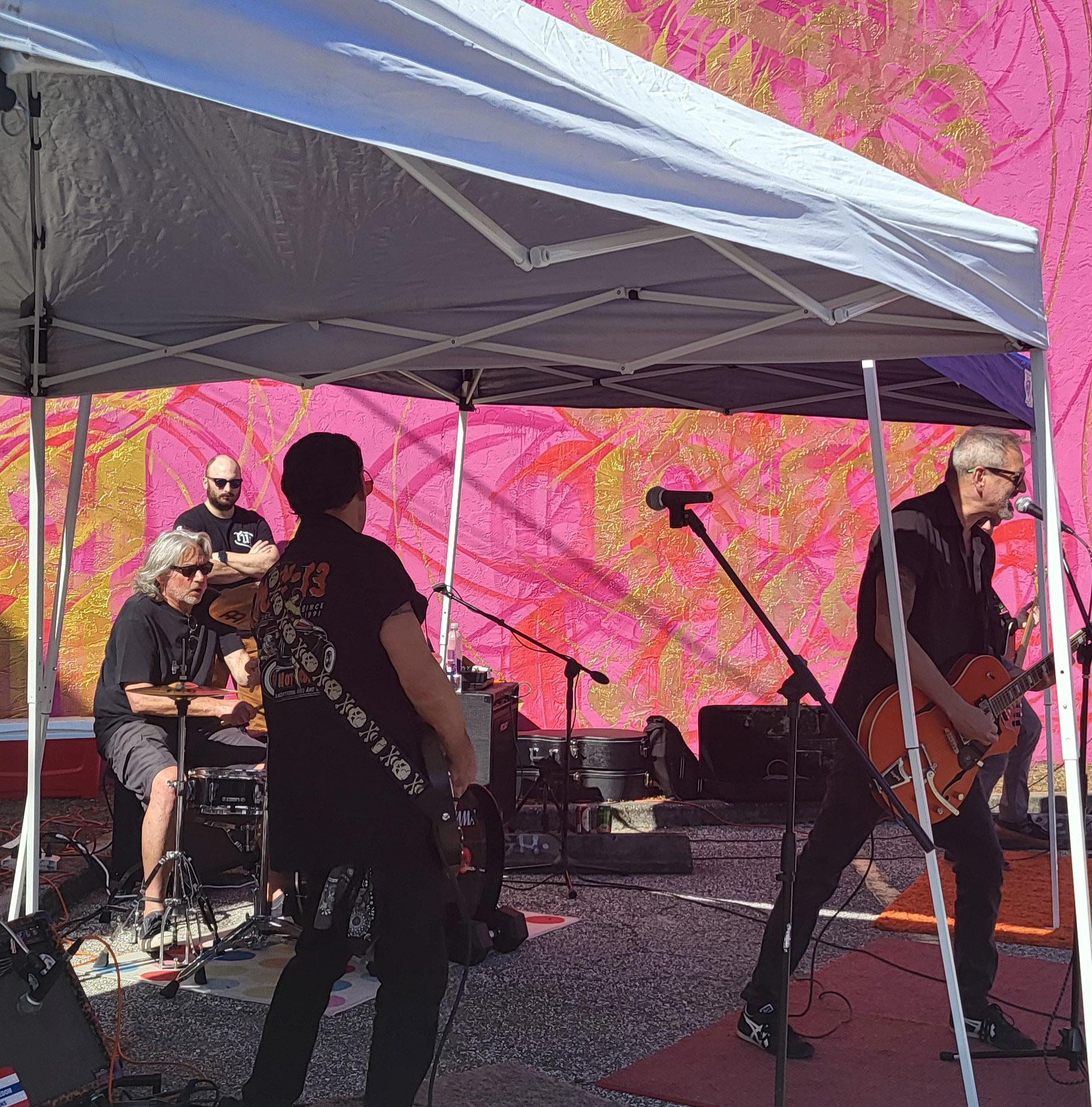 Tommy stands with guitar next to other guitarist, Jamey, on an outside stage.