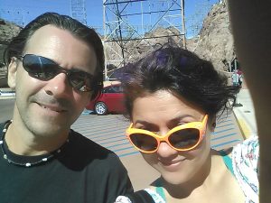 Tommy on the left, Mimi on the right. Mimi is wearing orange sunglasses. They are smiling. They are at the Hoover Dam.